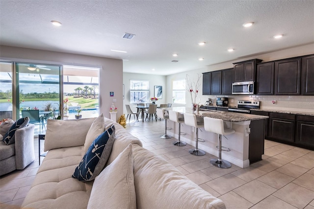 kitchen featuring a kitchen breakfast bar, a healthy amount of sunlight, a kitchen island with sink, and appliances with stainless steel finishes