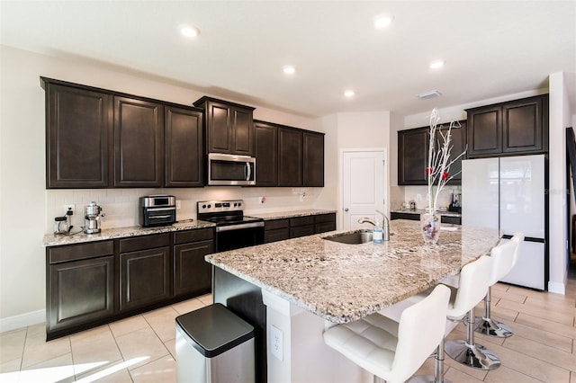 kitchen featuring a breakfast bar, sink, appliances with stainless steel finishes, and an island with sink