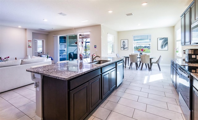 kitchen with a wealth of natural light, stainless steel appliances, a kitchen island with sink, and sink