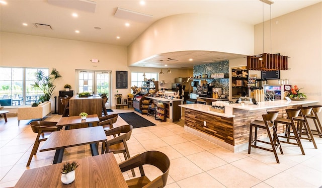 kitchen with kitchen peninsula, light tile patterned floors, decorative light fixtures, and a high ceiling