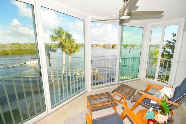 sunroom / solarium featuring ceiling fan and a water view