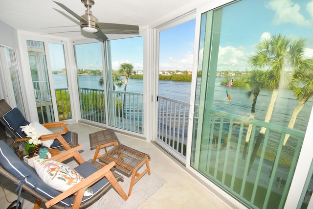 sunroom featuring ceiling fan and a water view