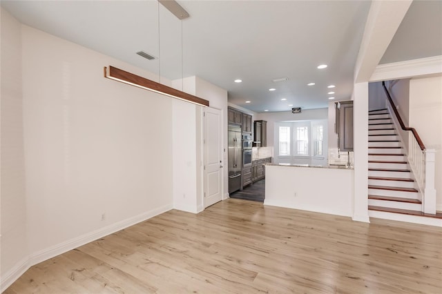 kitchen with kitchen peninsula, dark brown cabinets, light hardwood / wood-style floors, and tasteful backsplash