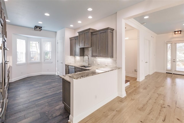 kitchen featuring dishwasher, light stone counters, a wealth of natural light, and sink