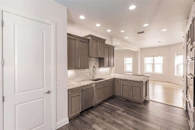 kitchen featuring dishwasher, sink, dark hardwood / wood-style flooring, kitchen peninsula, and decorative light fixtures