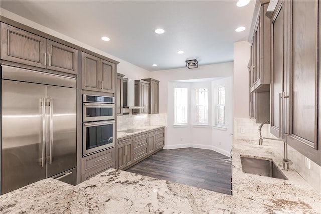 kitchen featuring dark hardwood / wood-style flooring, light stone countertops, appliances with stainless steel finishes, and tasteful backsplash