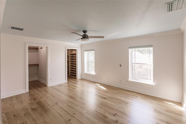 unfurnished bedroom with ceiling fan, light hardwood / wood-style floors, a spacious closet, and multiple windows