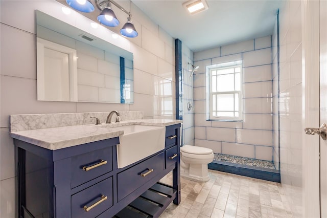 bathroom with vanity, toilet, and a tile shower