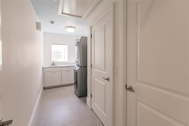 hallway featuring light tile patterned floors, stacked washer and dryer, and sink