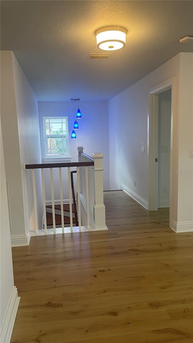 corridor with wood-type flooring and a textured ceiling