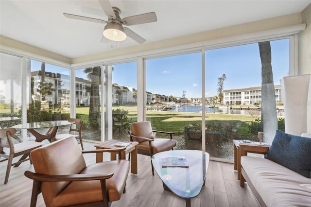 sunroom / solarium with ceiling fan, a water view, and a wealth of natural light