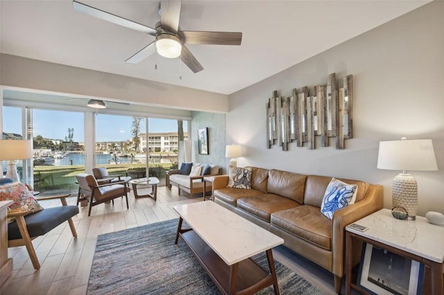 living room with ceiling fan, a water view, and hardwood / wood-style flooring