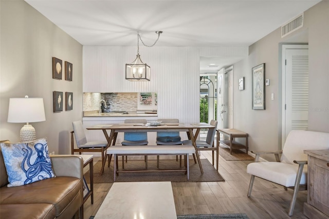 dining area featuring hardwood / wood-style floors, a notable chandelier, and sink