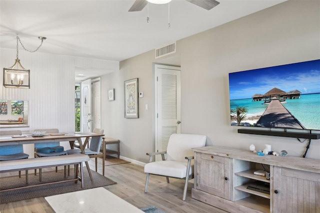 living room featuring light hardwood / wood-style floors and ceiling fan with notable chandelier