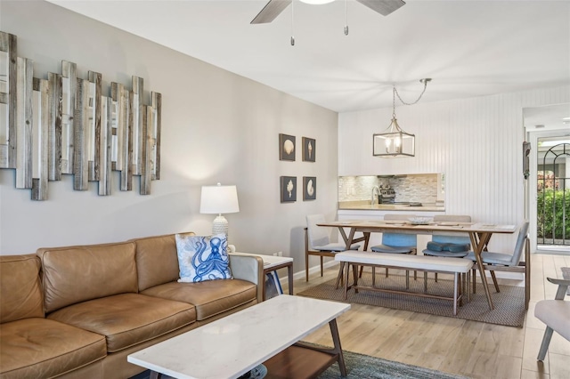 living room with light hardwood / wood-style flooring and ceiling fan with notable chandelier