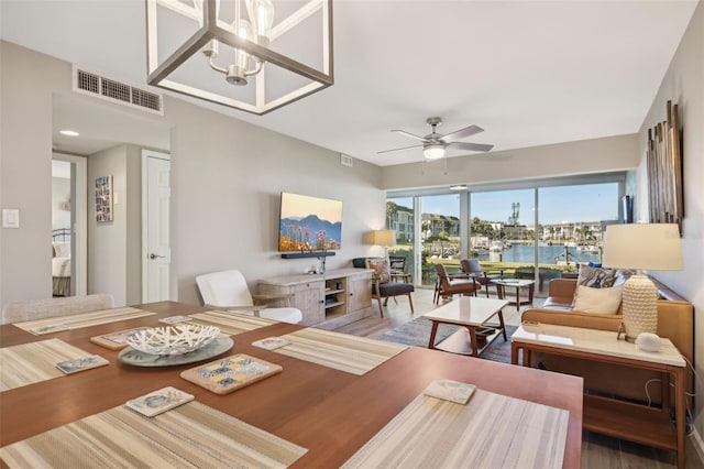 dining space with wood-type flooring and ceiling fan with notable chandelier