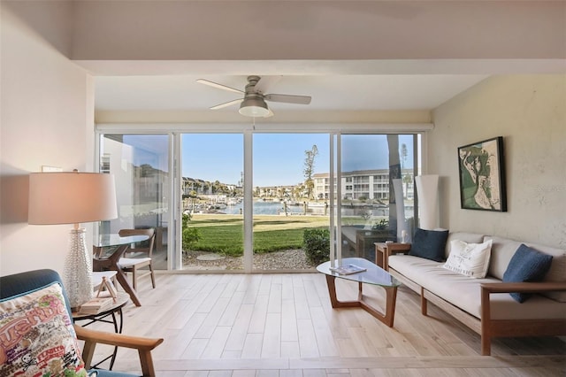 sunroom / solarium with ceiling fan and a water view