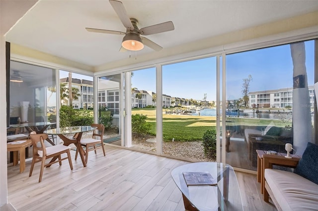 sunroom featuring a water view and ceiling fan