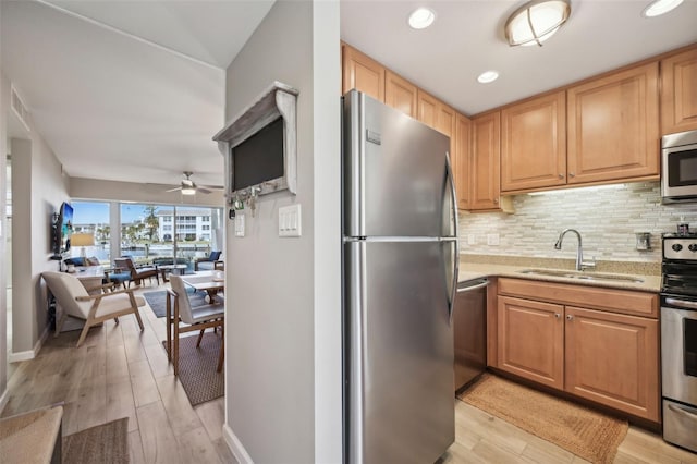 kitchen featuring ceiling fan, sink, stainless steel appliances, and light wood-type flooring