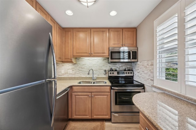 kitchen with light stone counters, sink, appliances with stainless steel finishes, and tasteful backsplash