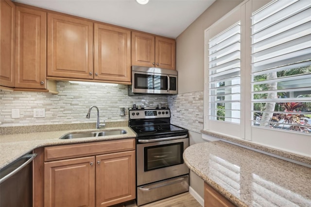 kitchen featuring light stone countertops, sink, appliances with stainless steel finishes, and tasteful backsplash