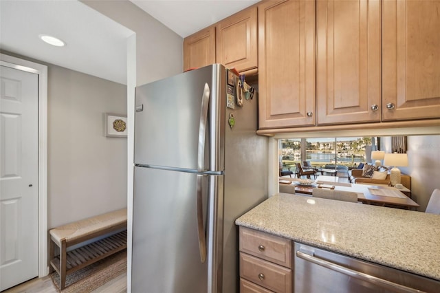 kitchen featuring light stone countertops, stainless steel appliances, and light wood-type flooring