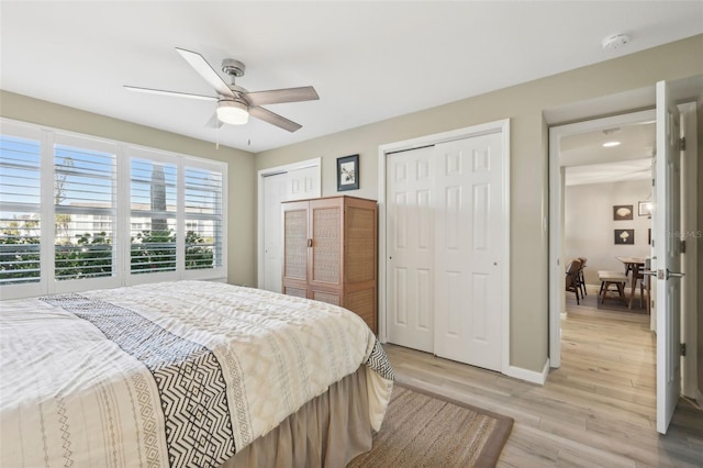 bedroom with ceiling fan, light hardwood / wood-style flooring, and two closets