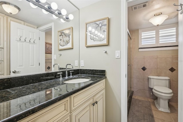 bathroom with vanity, tile walls, tile patterned flooring, toilet, and a shower with shower door