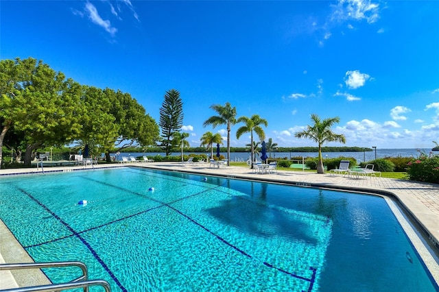 view of swimming pool featuring a water view and a patio