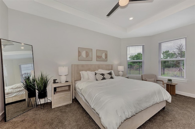 carpeted bedroom featuring ceiling fan and a tray ceiling