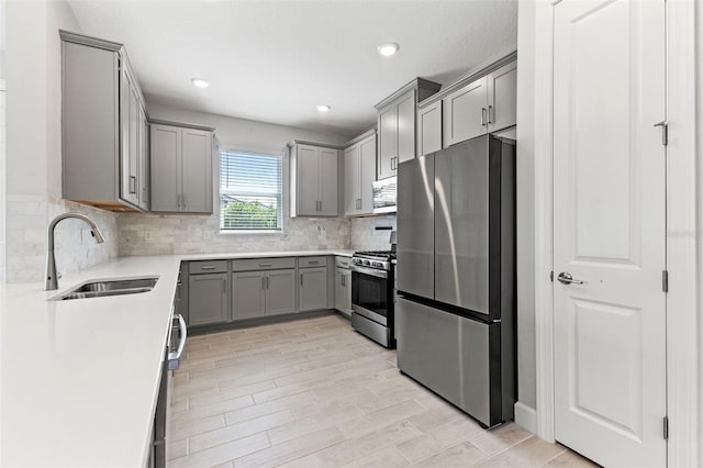 kitchen featuring tasteful backsplash, stainless steel appliances, gray cabinets, and sink