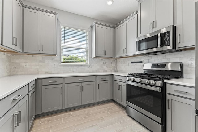 kitchen with gray cabinetry, decorative backsplash, and appliances with stainless steel finishes