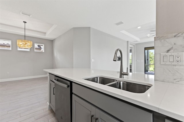 kitchen with gray cabinets, a tray ceiling, dishwasher, and decorative light fixtures