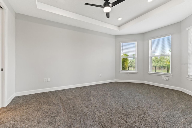 empty room with carpet flooring, ceiling fan, and a tray ceiling