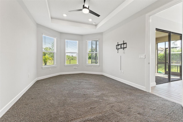 unfurnished room featuring a tray ceiling, ceiling fan, and carpet