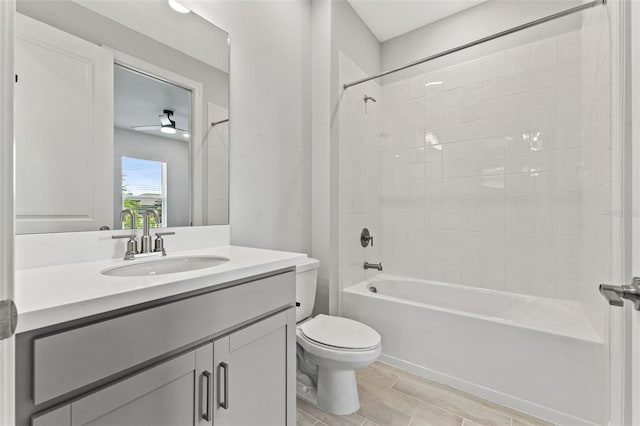 full bathroom featuring tiled shower / bath, vanity, and toilet