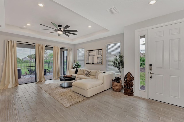 living room with ceiling fan and a tray ceiling