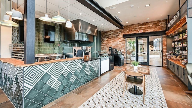 kitchen with tile patterned flooring, decorative light fixtures, and brick wall