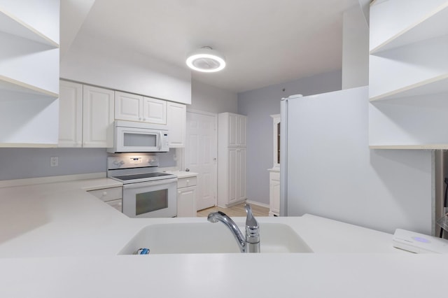 kitchen with white appliances, white cabinetry, and sink