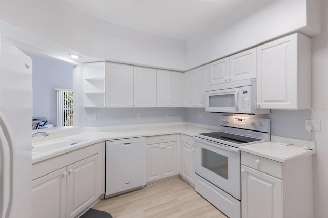 kitchen featuring white cabinets, light hardwood / wood-style floors, white appliances, and sink