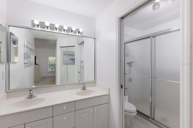 bathroom with tile patterned floors, vanity, toilet, and a shower with shower door