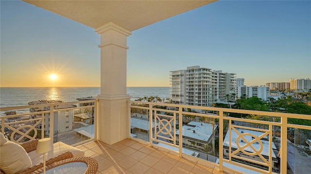 balcony at dusk featuring a water view