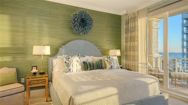 bedroom featuring access to outside, a water view, hardwood / wood-style flooring, and ornamental molding