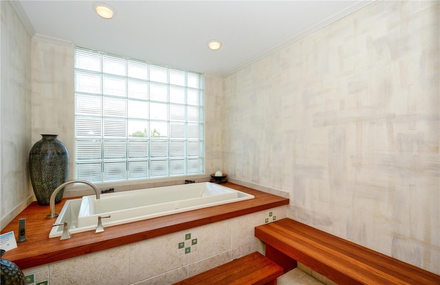 bathroom with a relaxing tiled tub, crown molding, and tile walls