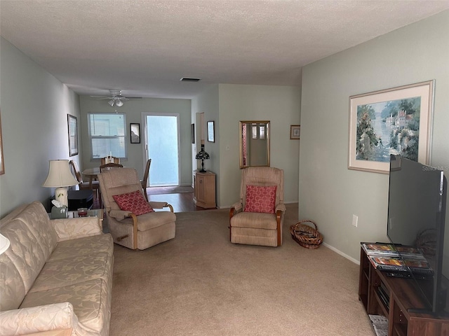 carpeted living room with ceiling fan and a textured ceiling