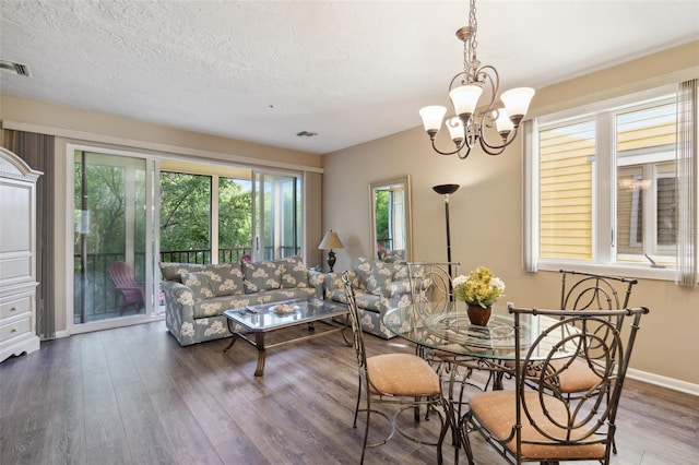 dining space featuring a textured ceiling, a chandelier, and dark hardwood / wood-style floors