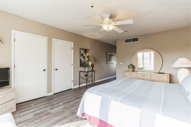 bedroom with multiple closets, ceiling fan, and light hardwood / wood-style floors