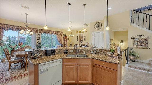 kitchen with white dishwasher, sink, pendant lighting, a notable chandelier, and an island with sink