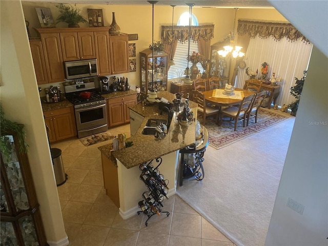 kitchen featuring light tile patterned flooring, appliances with stainless steel finishes, hanging light fixtures, and sink