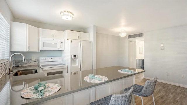 kitchen with white appliances, hardwood / wood-style flooring, white cabinetry, and sink